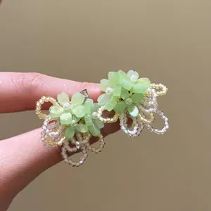 Close-up of green chiffon flower earrings with delicate beaded tassels and silver needles