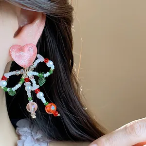 Close-up of glass beaded bow heart ear clips with colorful crystal details on model.