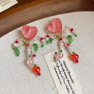 Detailed close-up of handmade pink heart-shaped glass bead bow clip-on earrings
