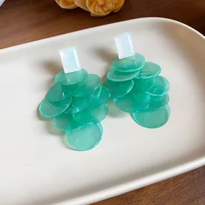 Detailed macro view of elegant green chiffon petal tassel earrings on a minimalist tray