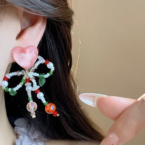 Detail view showing the delicate heart texture and beaded bow of the clip-on earring