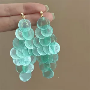 Close-up detail of mint green translucent petal-like disc tassel earrings with golden stud tops.