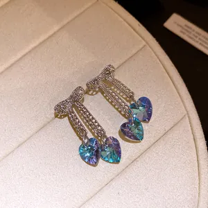 Macro view of sparkling bow tassel earrings with iridescent blue heart crystals