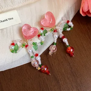 Close-up detail of handmade pink heart beaded clip-on earrings with floral accents