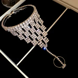 Dettaglio di un bracciale a mano in maglia di strass con anello su velluto nero