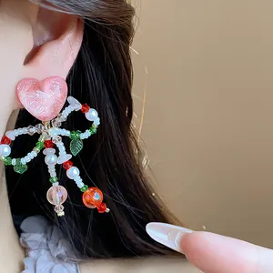 Close-up detail of a sweet pink glass beaded bow heart ear clip shown on a woman's ear