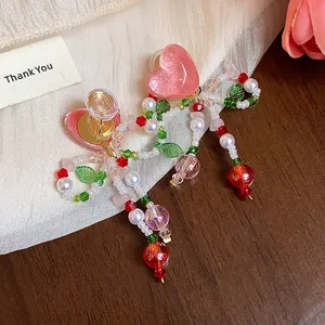 Macro view of handmade glass beaded bow earrings with pink resin heart and cherry dangles