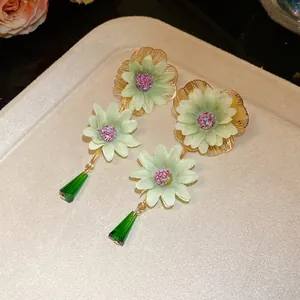 Detailed shot of elegant green chiffon flower earrings with dark green crystal drops