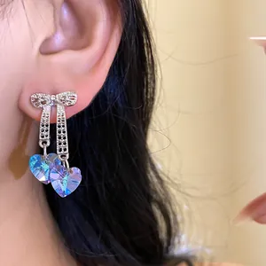 Detailed view of iridescent heart crystal earrings with sparkling silver bow design