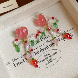 Detail of pink heart glass beaded bow clip-on earrings for women with sweet style