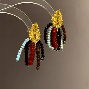 Detailed view of ethnic style gold leaf earrings with colorful beaded tassel jewelry
