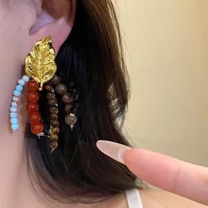 Detailed macro view of ethnic style golden leaf tassel earrings with colorful beads