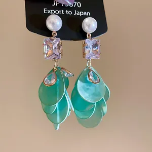 Close-up detail of elegant green floral tassel earrings with pearl and crystal accents.