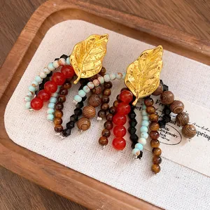 Detail view of ethnic vintage earrings with gold leaf and colorful beaded tassels