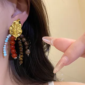 Close-up of ethnic vintage tassel earring with gold leaf and mixed beads.