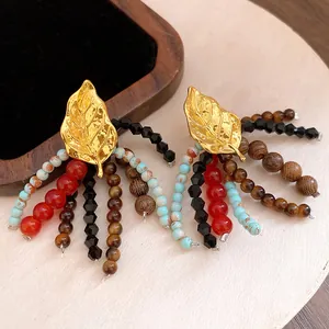 Close-up detail of ethnic style leaf tassel earrings with mixed stone and wood beads.