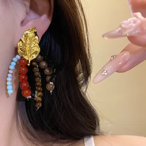 Detailed macro of gold leaf tassel earring with colorful ethnic stone and wood beads