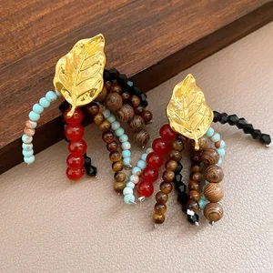 Close-up of ethnic retro tassel earrings featuring gold leaf, stone, and wood beads