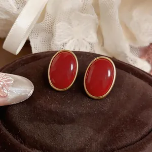 Primo piano di orecchini vintage ovali in resina rossa vibrante con montatura dorata