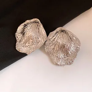 Detailed view of textured silver leaf earrings with intricate pleated metal design
