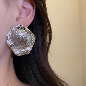 Detailed close-up view of elegant silver metallic wrinkled leaf stud earrings on model