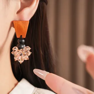 Close-up of vintage earrings featuring brown wood trapezoid and cluster glass beads
