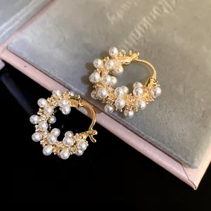 Detailed close-up of 18k gold-plated hoop earrings with clustered pearls and zircons.