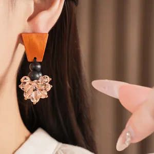 Close-up view of vintage brown wood and pink glass bead tassel earring on model's ear