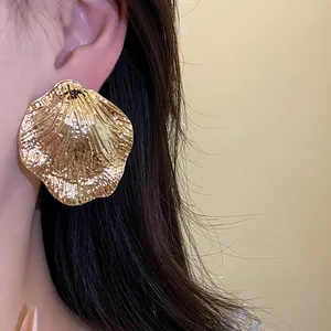 Detailed view of large gold metallic pleated leaf stud earring with radiant texture