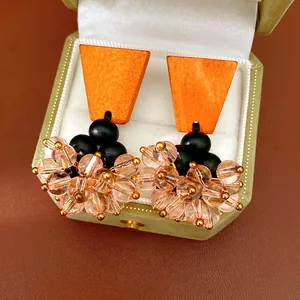 Detail of vintage earrings featuring orange wood blocks and champagne glass bead clusters.
