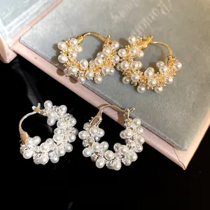 Close-up of elegant pearl and zircon hoop earrings in gold and silver finish
