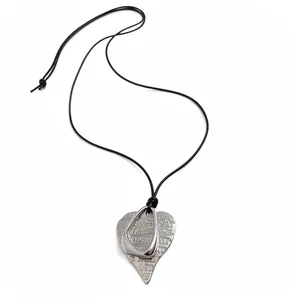 Minimalist silver heart pendant necklace with artistic engraved text on a sleek black cord.