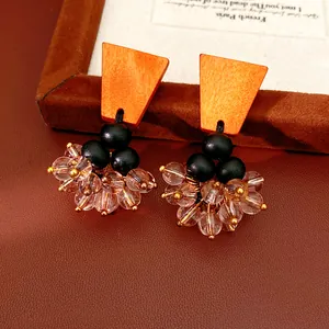Detailed close-up of retro ethnic style earrings with orange wood and glass beads.