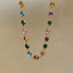 Détail d'un bracelet vintage en chaîne dorée avec des pierres ovales en résine colorée
