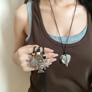 Detailed view of silver flower and fishbone pendants on black cord necklaces
