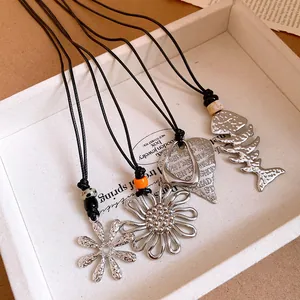 Detail view of silver flower and fishbone pendants on black cord necklaces