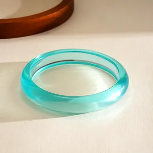 Gros plan détaillé d'un bracelet en résine turquoise translucide sur un fond texturé