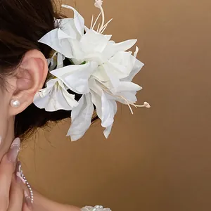 Close-up detail of an elegant white fabric flower hair clip with delicate pearl accents