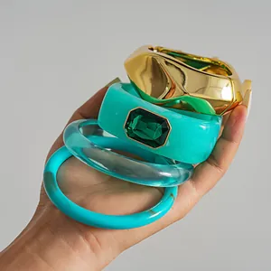 Vue détaillée de bracelets empilés élégants en résine et métal doré avec pierre verte.