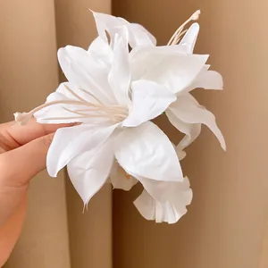 Detailed macro shot of an elegant white fabric flower hair clip with realistic stamens.