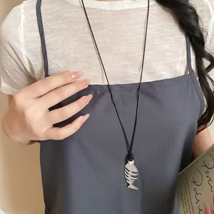 Close-up of a silver fishbone pendant necklace worn by a female model for fashion styling