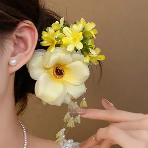 Close-up detail of yellow fabric flower hair clip with elegant pearl tassels on model