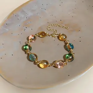 Détail d'un bracelet vintage réglable avec pierres de résine ovales colorées dorées.
