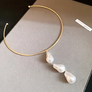 Elegant gold metal choker necklace with three baroque pearl pendants on gray background