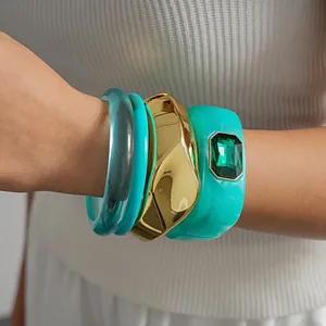 Gros plan de bracelets géométriques en résine turquoise et or sertis de strass chic
