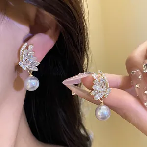Detail view of 18k gold plated butterfly earrings with zircon and pearls.