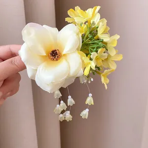 Elegant detail of a fabric flower hair clip with delicate pearl tassels and yellow buds.
