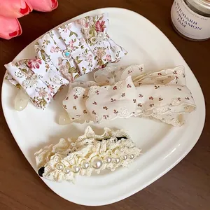 Set of sweet floral fabric bow and lace pearl hair clips displayed on an elegant white plate