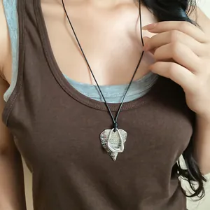 Close-up of stylish silver heart pendant necklace with black cord on a brown top.