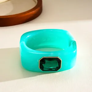 Détail d'un bracelet jonc en résine marbrée sarcelle avec un grand cristal vert émeraude